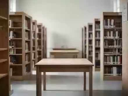 Ein minimalistischer Arbeitsbereich in einer Bibliothek mit leeren Holztischen und Bücherregalen im Hintergrund. - Foto: über boerse-global.de