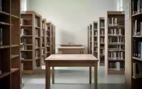 Ein minimalistischer Arbeitsbereich in einer Bibliothek mit leeren Holztischen und Bücherregalen im Hintergrund. - Foto: über boerse-global.de