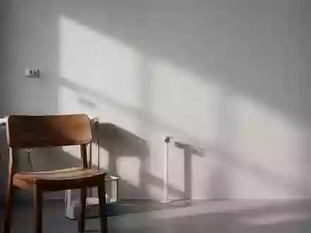 Ein minimalistischer, ruhiger Behandlungsraum mit einem hölzernen Stuhl und sanftem Licht vor einer neutralen Wand. - Foto: über boerse-global.de