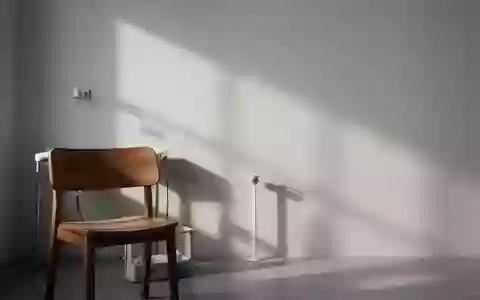 Ein minimalistischer, ruhiger Behandlungsraum mit einem hölzernen Stuhl und sanftem Licht vor einer neutralen Wand. - Foto: über boerse-global.de