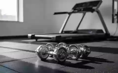Leerer, moderner Fitnessraum mit Hanteln auf einem Gummiboden und einem Laufband im Hintergrund. - Foto: über boerse-global.de