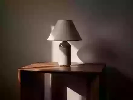 Ein minimalistischer Beistelltisch mit einer unbeleuchteten Lampe in einem schlichten, dunklen Raum. - Foto: über boerse-global.de