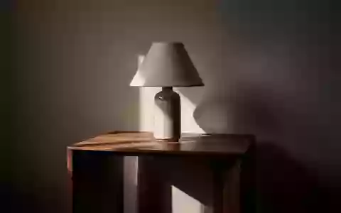 Ein minimalistischer Beistelltisch mit einer unbeleuchteten Lampe in einem schlichten, dunklen Raum. - Foto: über boerse-global.de