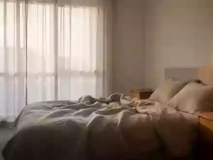 Ein ruhiges, minimalistisches Schlafzimmer bei Tageslicht mit einem ungemachten Bett und einem Holznachttisch. - Foto: über boerse-global.de