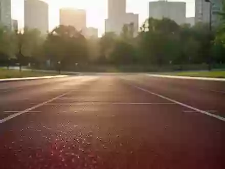 Eine leere Laufbahn in einem Stadtpark bei Sonnenuntergang, die den sportlichen Einsatzbereich der Kopfhörer symbolisiert. - Foto: über boerse-global.de