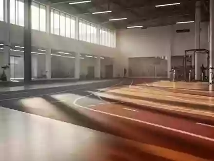Eine leere, moderne Laufbahn in einer hellen Sporthalle mit natürlichem Lichteinfall und poliertem Holzboden. - Foto: über boerse-global.de