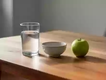 Ein Glas Wasser und ein Apfel auf einem schlichten Holztisch in einer ruhigen, hellen Umgebung. - Foto: über boerse-global.de