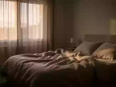 Ein ruhiges, in sanftes Morgenlicht getauchtes Schlafzimmer mit einem ungemachten Bett, das eine friedliche Atmosphäre vermittelt. - Foto: über boerse-global.de
