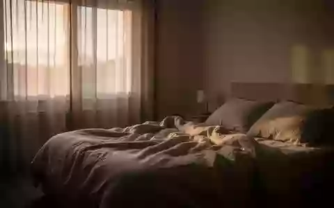 Ein ruhiges, in sanftes Morgenlicht getauchtes Schlafzimmer mit einem ungemachten Bett, das eine friedliche Atmosphäre vermittelt. - Foto: über boerse-global.de