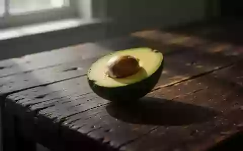 Eine halbierte reife Avocado liegt auf einem rustikalen dunklen Holztisch im natürlichen Licht. - Foto: über boerse-global.de