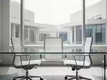 Ein minimalistischer, moderner Büroarbeitsplatz mit leerem Schreibtisch vor einer hellen Fensterfront. - Foto: über boerse-global.de