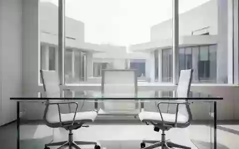 Ein minimalistischer, moderner Büroarbeitsplatz mit leerem Schreibtisch vor einer hellen Fensterfront. - Foto: über boerse-global.de