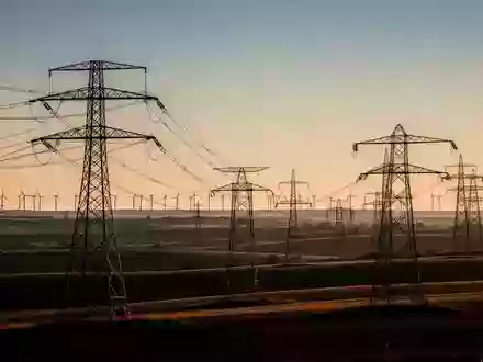 Hochspannungsmasten in einer weiten, ländlichen Landschaft bei Sonnenuntergang. - Foto: über boerse-global.de
