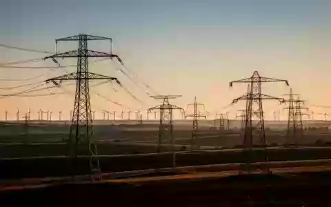Hochspannungsmasten in einer weiten, ländlichen Landschaft bei Sonnenuntergang. - Foto: über boerse-global.de