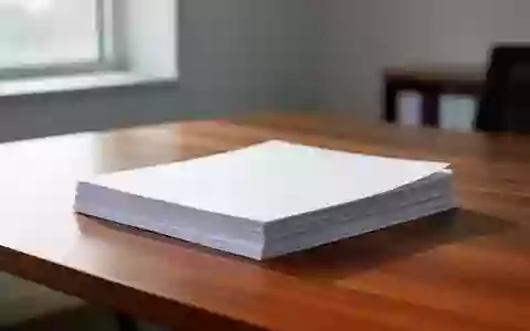 Ein ordentlicher, minimalistischer Arbeitsplatz mit einem Stapel leerer weißer Dokumente auf einem Holztisch bei Tageslicht. - Foto: über boerse-global.de