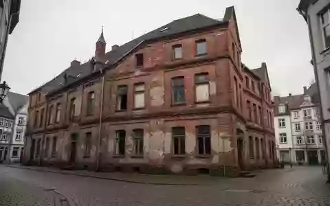 Ein historisches Backsteingebäude in einer ruhigen Stadtstraße bei bewölktem Himmel. - Foto: über boerse-global.de
