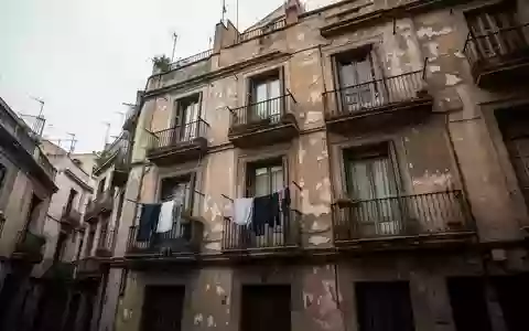 Fassade eines alten Wohnhauses in einem dicht besiedelten Viertel von Barcelona bei bewölktem Tageslicht. - Foto: über boerse-global.de