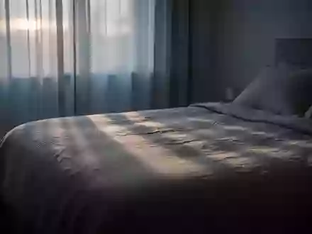 Ein ruhig wirkendes Schlafzimmer im sanften Licht der Morgendämmerung mit schlichten Textilien und ruhiger Atmosphäre. - Foto: über boerse-global.de