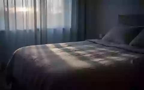 Ein ruhig wirkendes Schlafzimmer im sanften Licht der Morgendämmerung mit schlichten Textilien und ruhiger Atmosphäre. - Foto: über boerse-global.de
