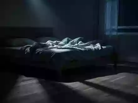Ein ungemachtes Bett in einem spärlich beleuchteten Schlafzimmer, in das sanftes Mondlicht durch ein Fenster fällt. - Foto: über boerse-global.de