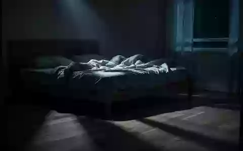 Ein ungemachtes Bett in einem spärlich beleuchteten Schlafzimmer, in das sanftes Mondlicht durch ein Fenster fällt. - Foto: über boerse-global.de