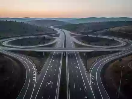 Eine weitläufige, moderne Autobahnkreuzung in der Dämmerung, umgeben von einer ruhigen Hügellandschaft. - Foto: über boerse-global.de