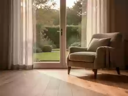 Ein sonnendurchflutetes Wohnzimmer mit einem bequemen Sessel neben einem Fenster mit Blick in einen ruhigen Garten. - Foto: über boerse-global.de