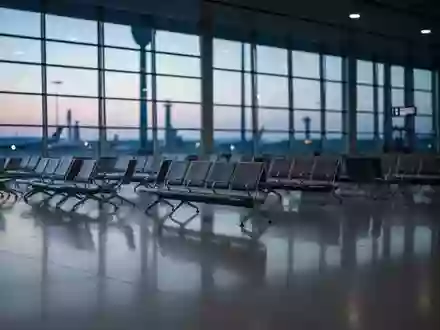 Ein weitläufiges, leeres Flughafenterminal in der Abenddämmerung mit minimalistischen Sitzreihen und großen Glasfronten. - Foto: über boerse-global.de