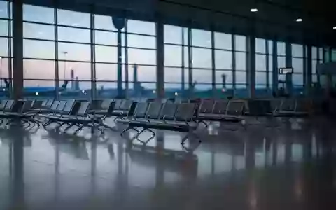Ein weitläufiges, leeres Flughafenterminal in der Abenddämmerung mit minimalistischen Sitzreihen und großen Glasfronten. - Foto: über boerse-global.de