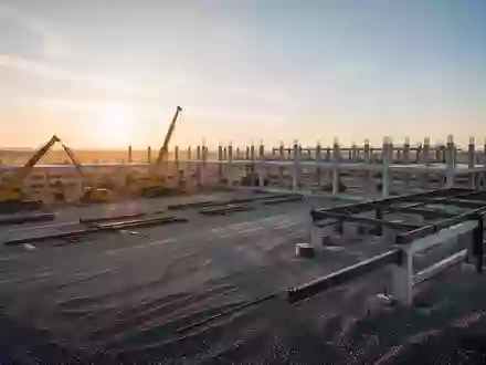 Eine weitläufige Baustelle für ein industrielles Großprojekt bei Sonnenaufgang mit schweren Maschinen und Betonstrukturen. - Foto: über boerse-global.de