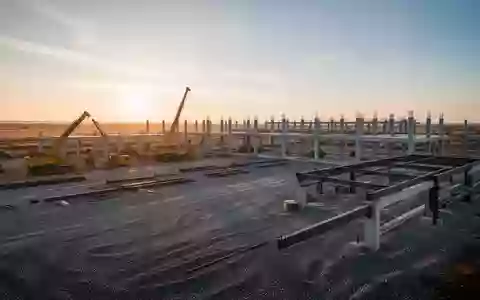 Eine weitläufige Baustelle für ein industrielles Großprojekt bei Sonnenaufgang mit schweren Maschinen und Betonstrukturen. - Foto: über boerse-global.de
