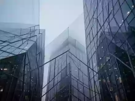 Moderne Glas- und Stahlfassade eines Bürogebäudes in der Dämmerung, die Ordnung und regulatorische Struktur symbolisiert. - Foto: über boerse-global.de