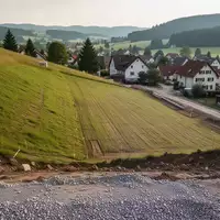 Eine unbebaute, abschüssige Baufläche an einem Hang in Adenau, vorbereitet für zukünftige Baumaßnahmen. - Foto: über boerse-global.de