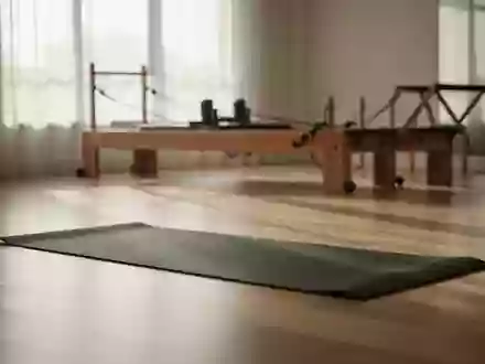 Ein minimalistischer, lichtdurchfluteter Trainingsraum mit einer ausgebreiteten Yogamatte und einem Pilates-Gerät im Hintergrund. - Foto: über boerse-global.de