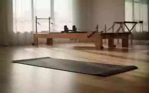 Ein minimalistischer, lichtdurchfluteter Trainingsraum mit einer ausgebreiteten Yogamatte und einem Pilates-Gerät im Hintergrund. - Foto: über boerse-global.de