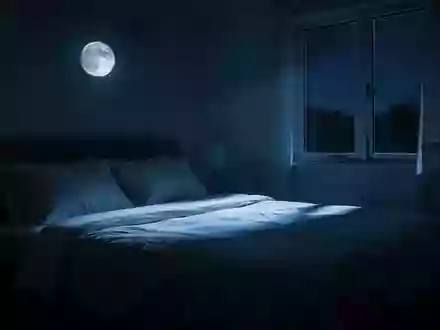Ein minimalistisch eingerichtetes Schlafzimmer in der Nacht, in dem sanftes Mondlicht durch ein Fenster auf ein unberührtes Bett fällt. - Foto: über boerse-global.de