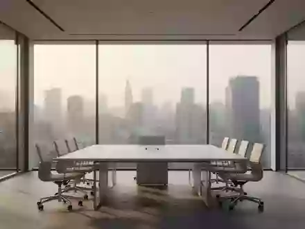 Ein minimalistischer, leerer Konferenzraum mit Glaswänden und Blick auf eine verschwommene Stadtlandschaft bei Tagesanbruch. - Foto: über boerse-global.de