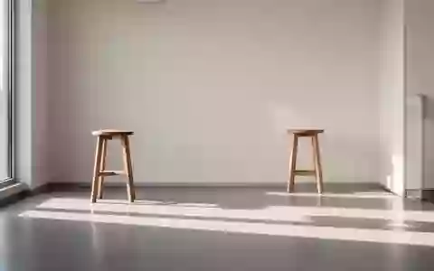 Ein minimalistischer, heller Untersuchungsraum in einer medizinischen Praxis mit einem leeren Holzschemel vor einer Wand. - Foto: über boerse-global.de