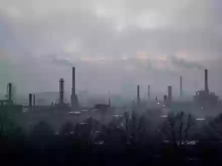 Dichte, dunstige Luftverschmutzung über einer urbanen Industrielandschaft bei Dämmerung. - Foto: über boerse-global.de