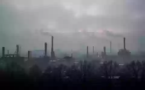 Dichte, dunstige Luftverschmutzung über einer urbanen Industrielandschaft bei Dämmerung. - Foto: über boerse-global.de