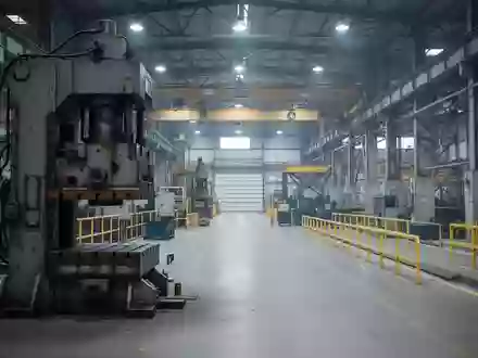 Industrielle Fertigungshalle mit einer schweren Metallpresse und Sicherheitsabsperrungen in einer sauberen Arbeitsumgebung. - Foto: über boerse-global.de