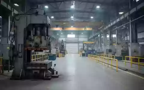 Industrielle Fertigungshalle mit einer schweren Metallpresse und Sicherheitsabsperrungen in einer sauberen Arbeitsumgebung. - Foto: über boerse-global.de