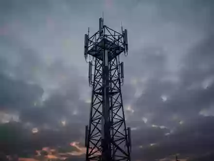 Ein Funkturm steht einsam vor einem bewölkten Abendhimmel als Symbol für die Mobilfunkinfrastruktur. - Foto: über boerse-global.de