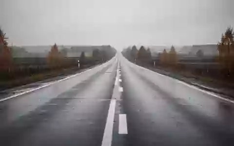 Eine leere, nasse Landstraße, die sich in einer trüben Herbstlandschaft bis zum Horizont erstreckt. - Foto: über boerse-global.de