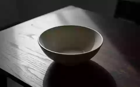 Eine leere, schlichte Keramikschale auf einem dunklen Holztisch in einer minimalistischen Umgebung. - Foto: über boerse-global.de