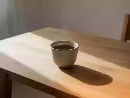 Eine schlichte Keramiktasse mit dunklem Kaffee auf einem Holztisch in hellem, natürlichem Tageslicht. - Foto: über boerse-global.de