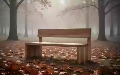 Eine leere Holzbank in einem nebligen Herbstpark mit herabgefallenem Laub am Boden. - Foto: über boerse-global.de