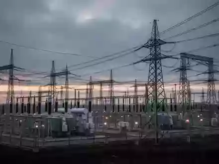 Ein weitläufiges, modernes Umspannwerk bei Dämmerung mit Hochspannungstransformatoren und Strommasten unter einem bewölkten Himmel. - Foto: über boerse-global.de