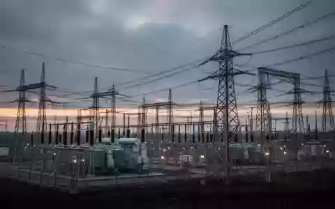 Ein weitläufiges, modernes Umspannwerk bei Dämmerung mit Hochspannungstransformatoren und Strommasten unter einem bewölkten Himmel. - Foto: über boerse-global.de