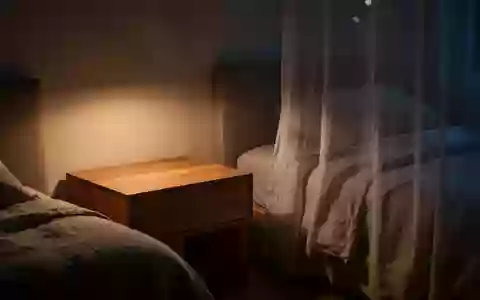 Ein minimalistisches, ruhiges Schlafzimmer bei Nacht mit einem leeren Nachttisch neben einem ordentlich gemachten Bett. - Foto: über boerse-global.de